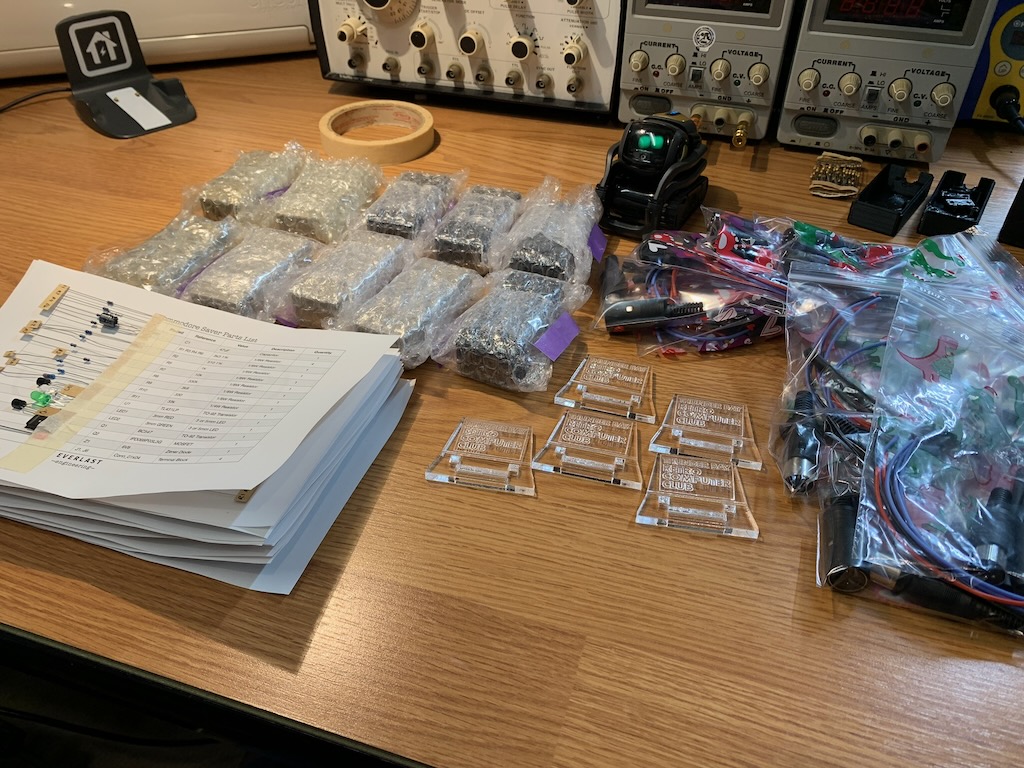 Assembled electronics kits, demo boards, and bagged component sets laid out for hobby clubs