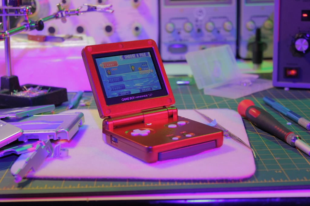 Game Boy Advance SP on a repair bench with a replacement shell fitted
