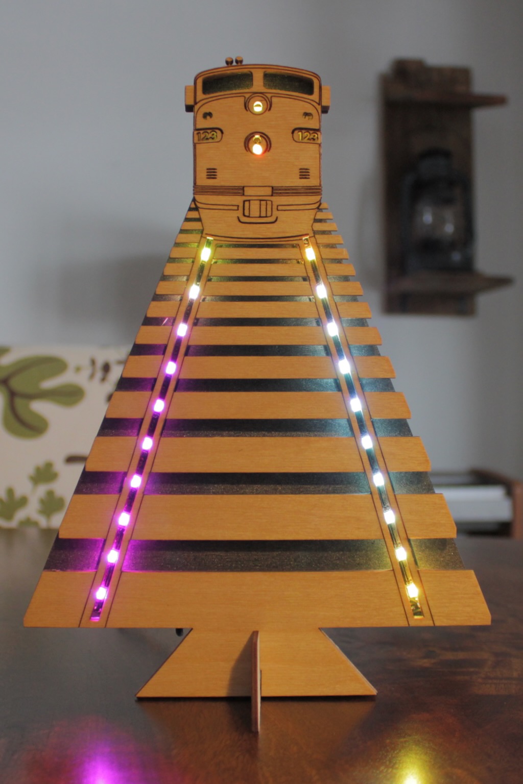 Laser cut wooden locomotive mounted on illuminated model track as a decorative art piece