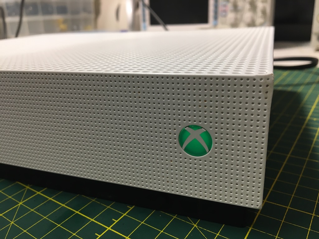 White Xbox One S console with an illuminated green Xbox sphere logo installed in the side vent